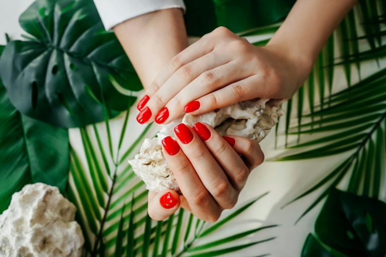 Manicured woman's nails with red nail polish.